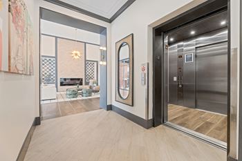A modern hallway with a wooden floor and a glass elevator